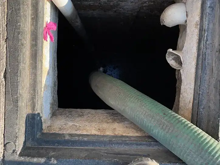 Técnico de Acuatec introduciendo manguera para desazolve de fosa séptica
